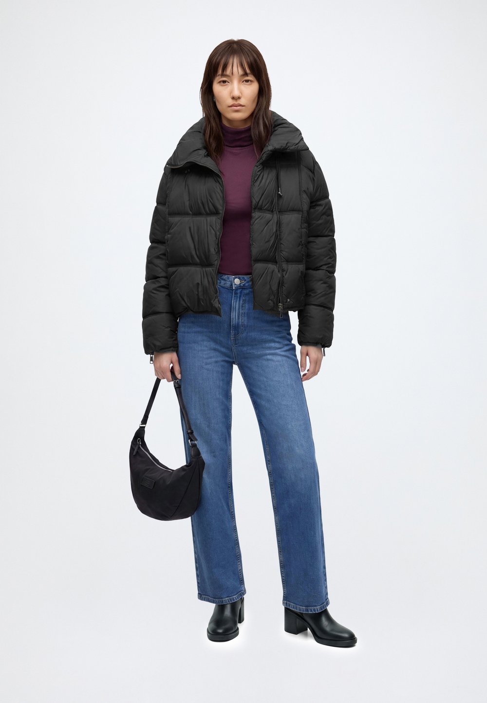 Cropped black puffer jacket over a burgundy turtleneck with blue jeans and black heeled boots