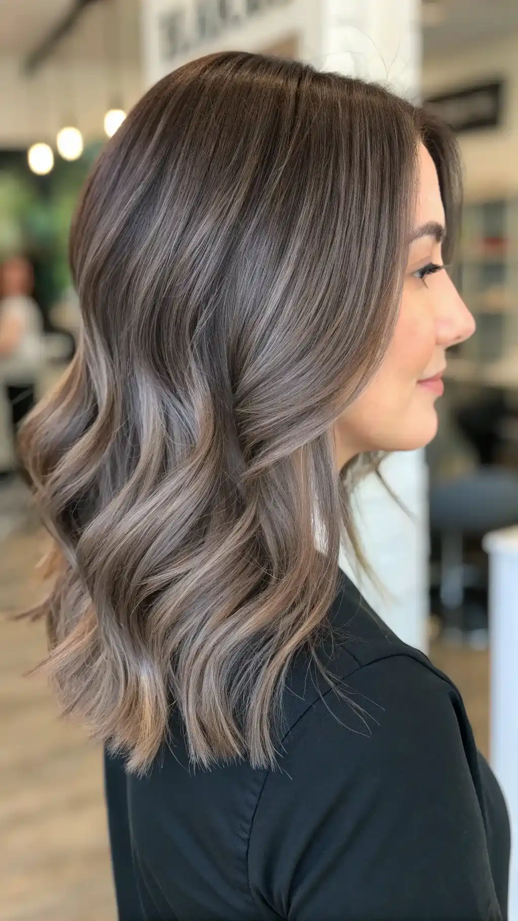 Dark ash-brown hair with smoky cool dimension in a sleek style