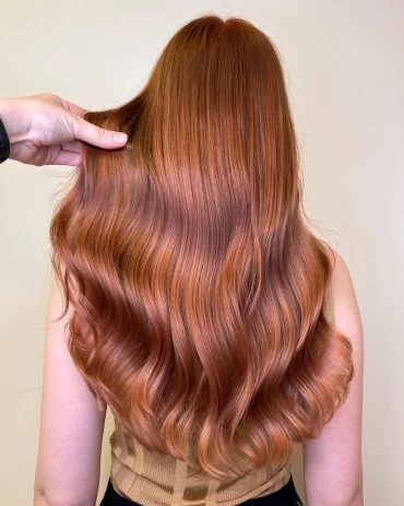 Long wavy dark strawberry blonde hair with copper glow, back view