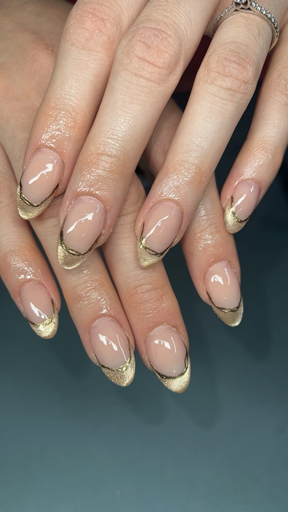 Classic French manicure on a nude base with metallic gold tips instead of white.