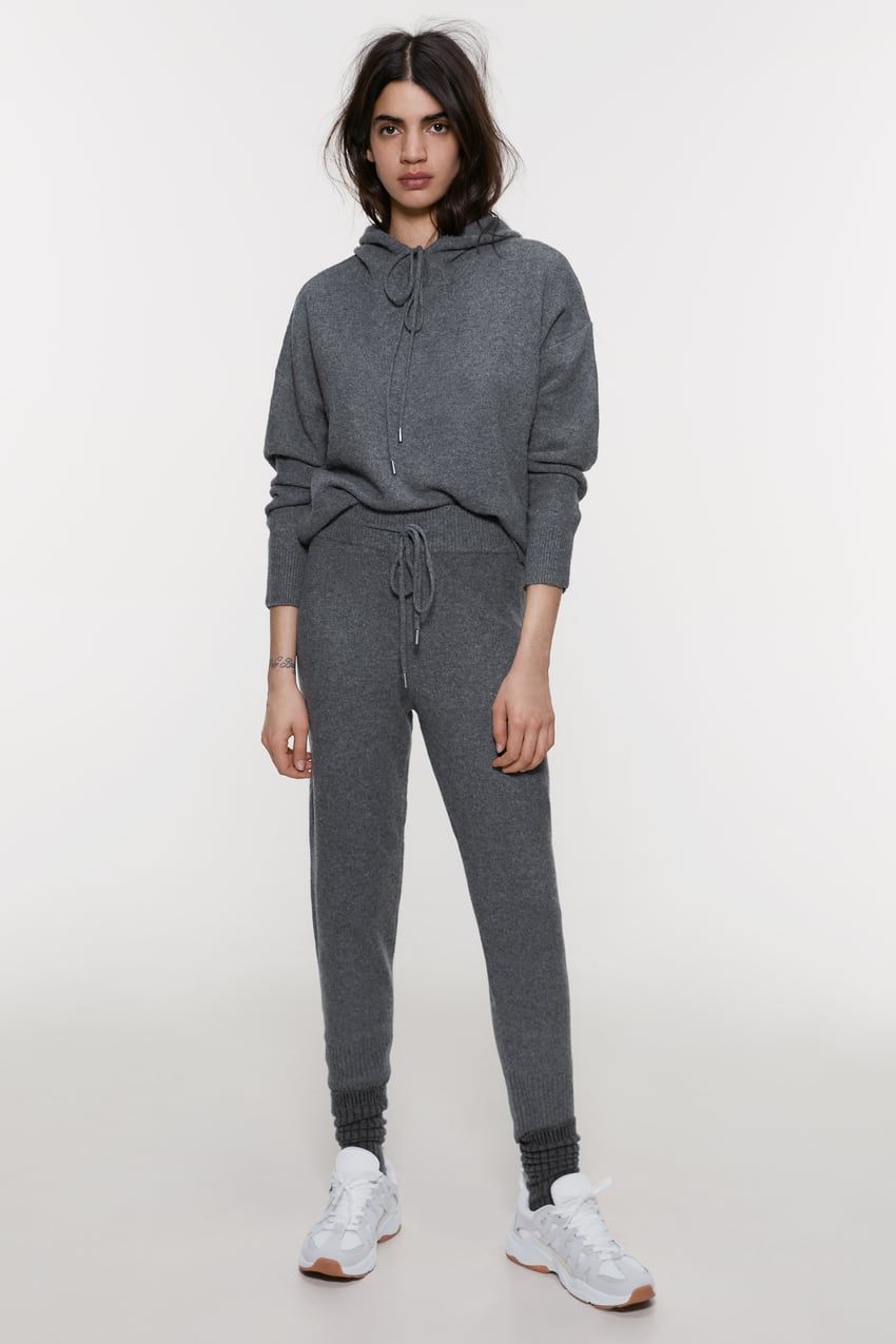 Woman in gray knit hoodie and matching joggers with white sneakers