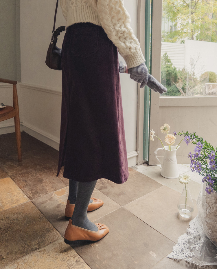 Cream cable-knit sweater with burgundy corduroy midi skirt, grey tights and tan ballet flats