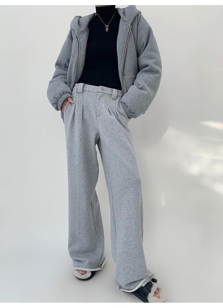 Person in gray wide-leg sweatpants, gray zip hoodie over black turtleneck and fuzzy slippers