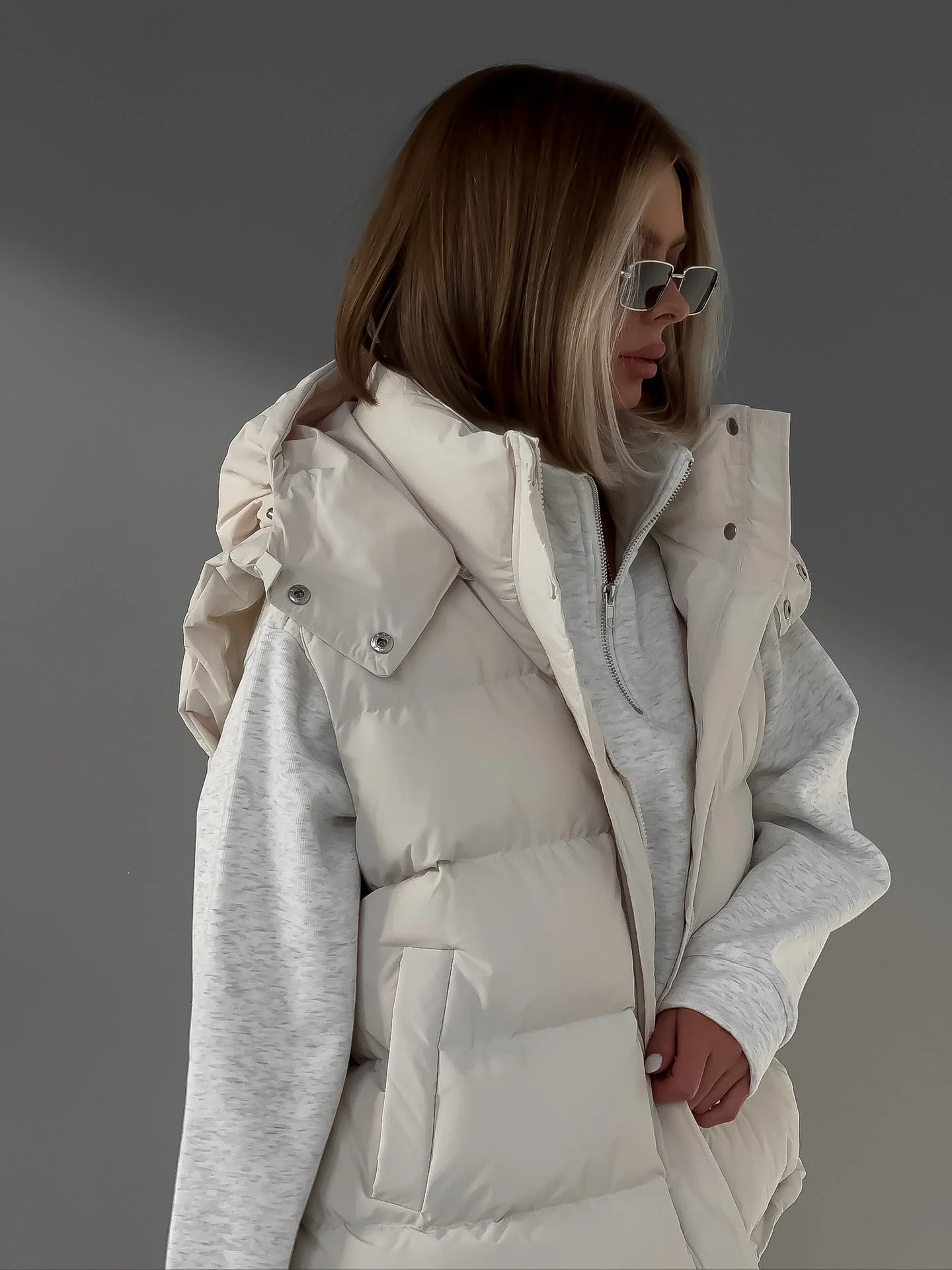Cream puffer vest layered over a heather gray hoodie