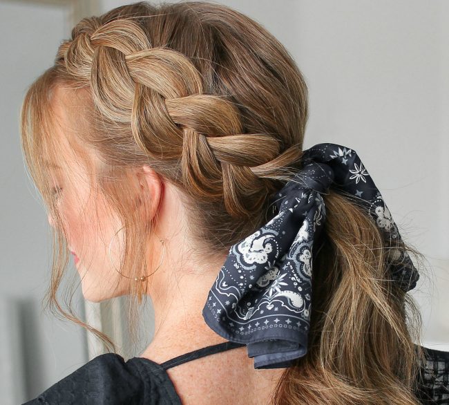 Dutch side braid flowing into a low ponytail tied with a black bandana scarf