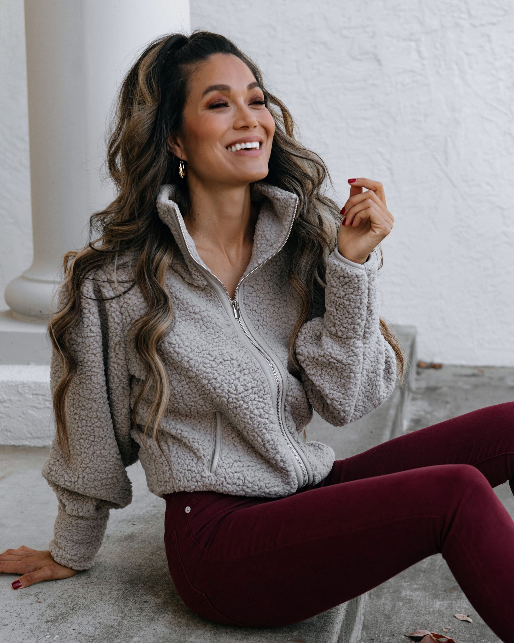 Woman in a grey sherpa fleece zip-up with burgundy jeans