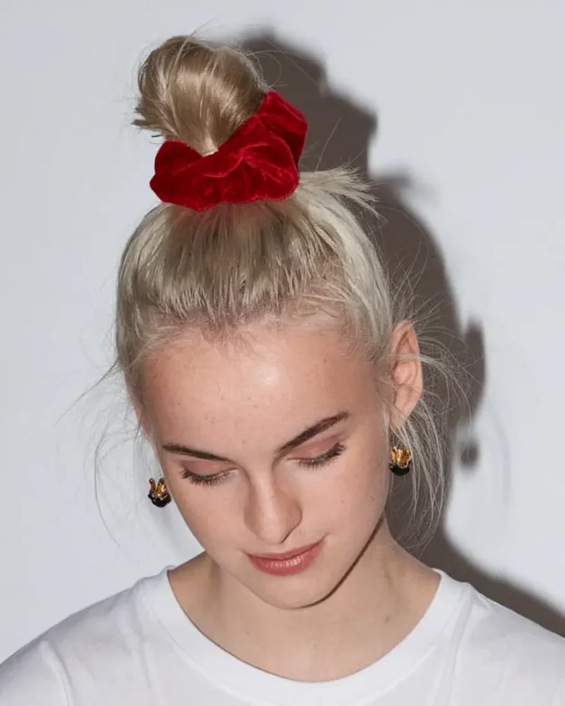 Front view of a high bun wrapped with a red velvet scrunchie