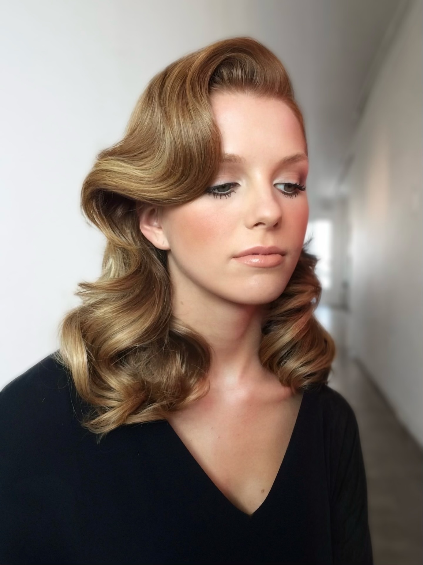 Elegant caramel-toned waves swooping from a side part on medium-length hair