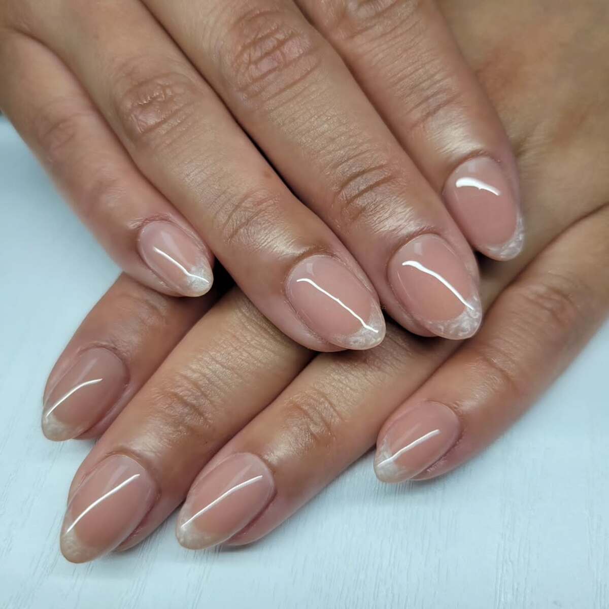 Short almond nails in blush nude with thin white french tips