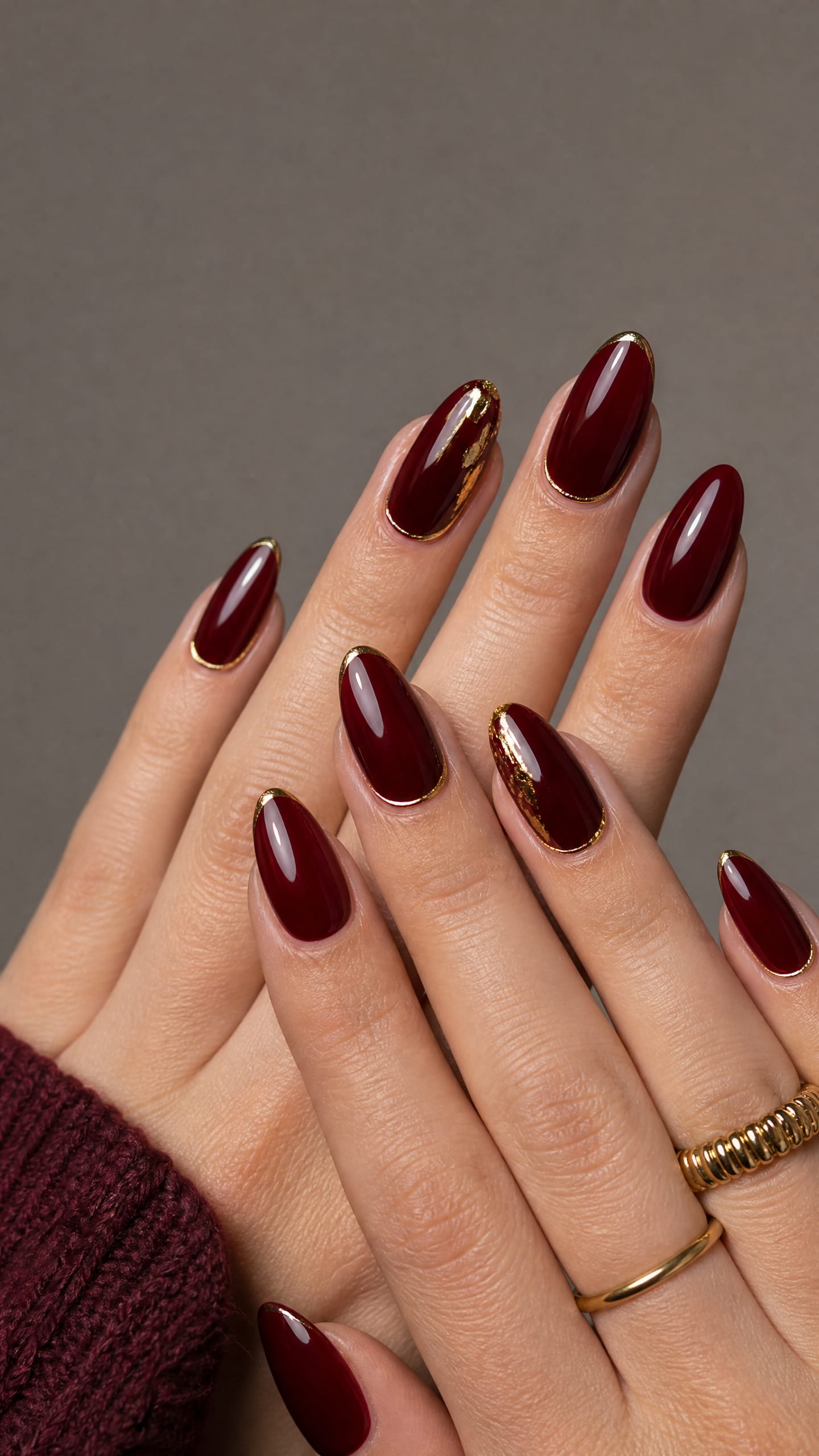 Wine red almond nails with gold foil edging around each nail