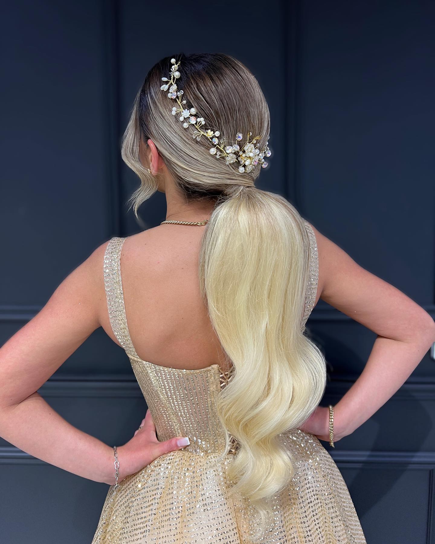Sleek low ponytail decorated with a pearl hair vine on blonde hair