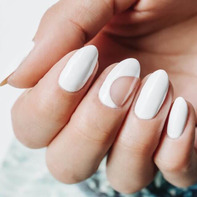 White nails with reverse half-moon negative space at the cuticle