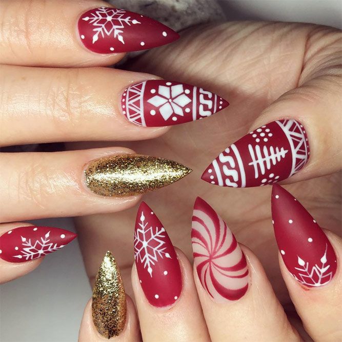 Matte red stiletto nails with white fair-isle sweater patterns and gold glitter accent nails