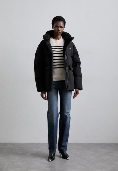 Woman in a striped long-sleeve top under a puffer jacket