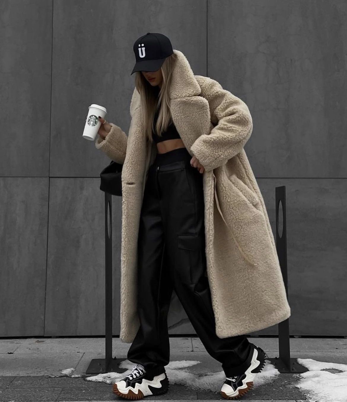 Woman in an oversized beige coat with faux leather pants, winter outfit