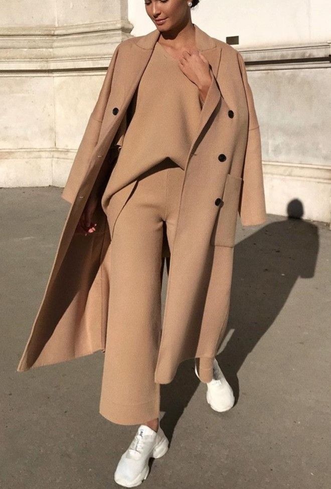 Woman in camel knit top and wide-leg pants with camel wool coat and white sneakers