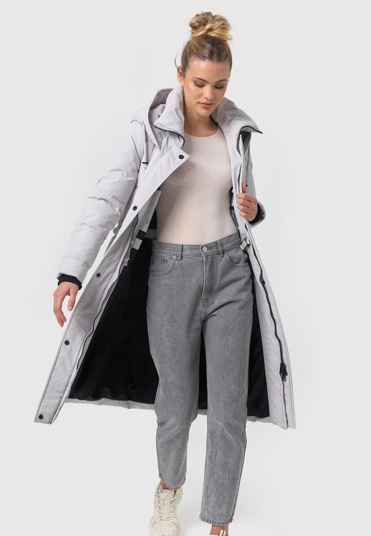 A light grey longline puffer parka worn open over a beige knit top, grey jeans and chunky sneakers.