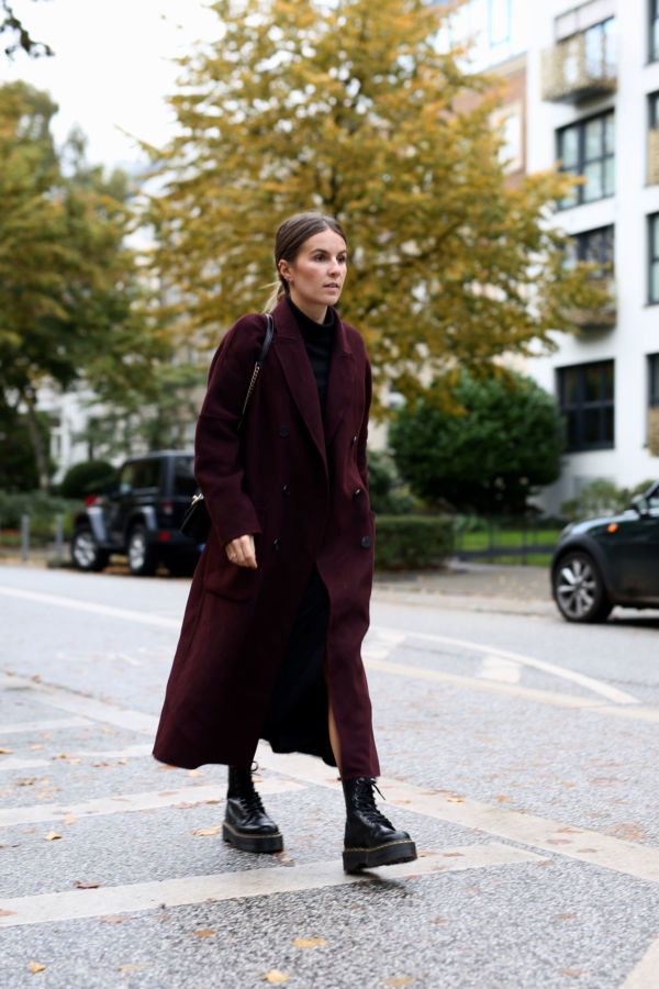 Woman in a burgundy wool coat with a midi dress and boots