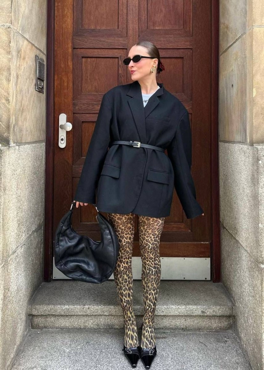 Woman in an oversized blazer, turtleneck and tailored trousers with a briefcase-style bag