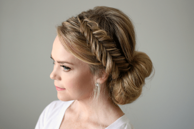 A fishtail braid wrapped into a low crown-like updo
