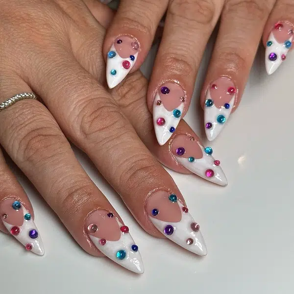 White French tips on stiletto nails scattered with pink blue and purple rhinestones