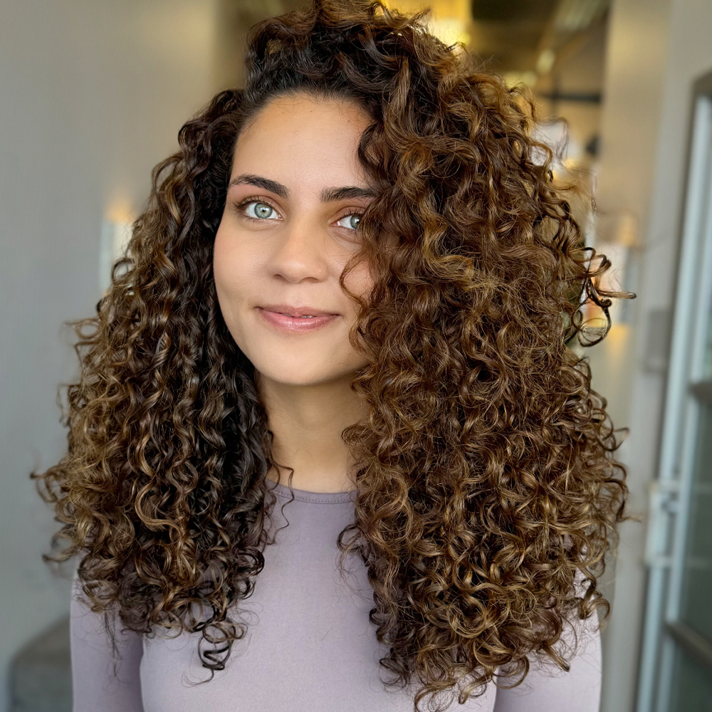 Curly hair in an all-over golden brown color with a voluminous diffused finish