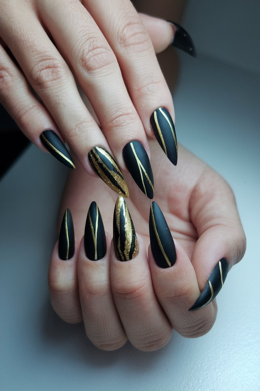 Matte Black with Gold Stripes: matte black stiletto nails with gold striping and glitter stripes