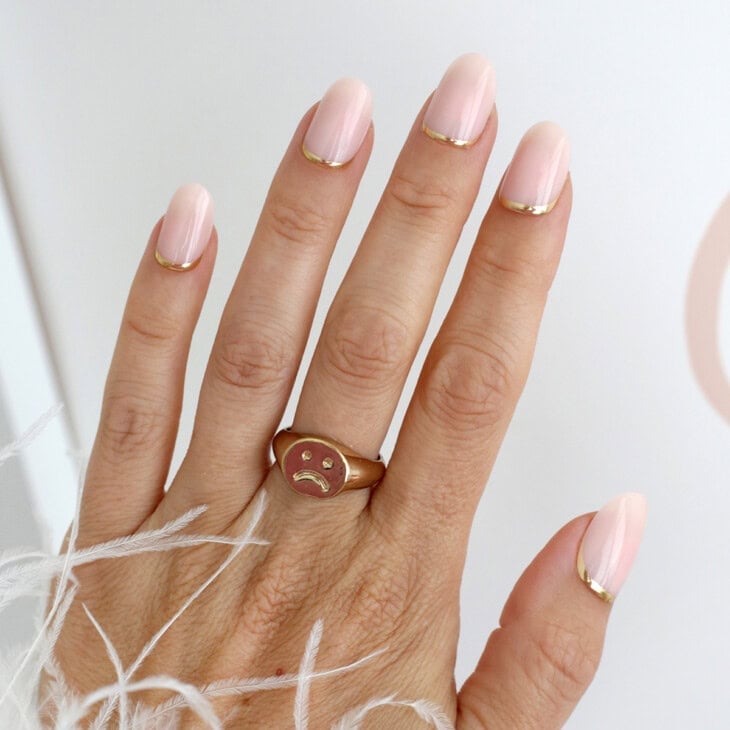 Nails with gold reverse French half-moon detailing at the cuticles