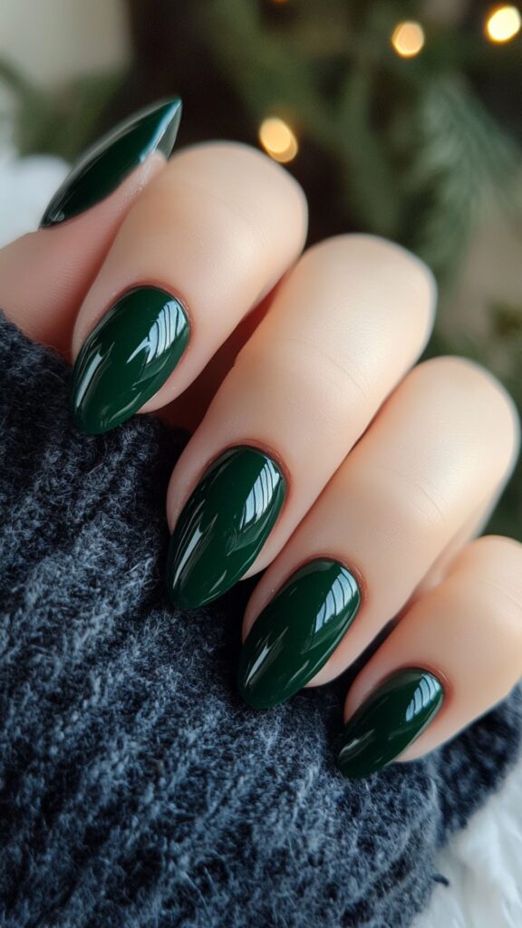 Medium almond nails in solid deep emerald green with a high-gloss finish