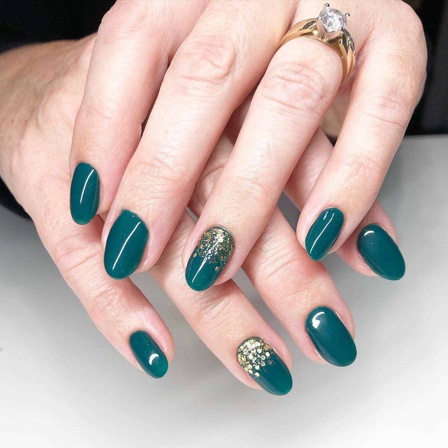 Short oval emerald green nails with gold glitter accent nails