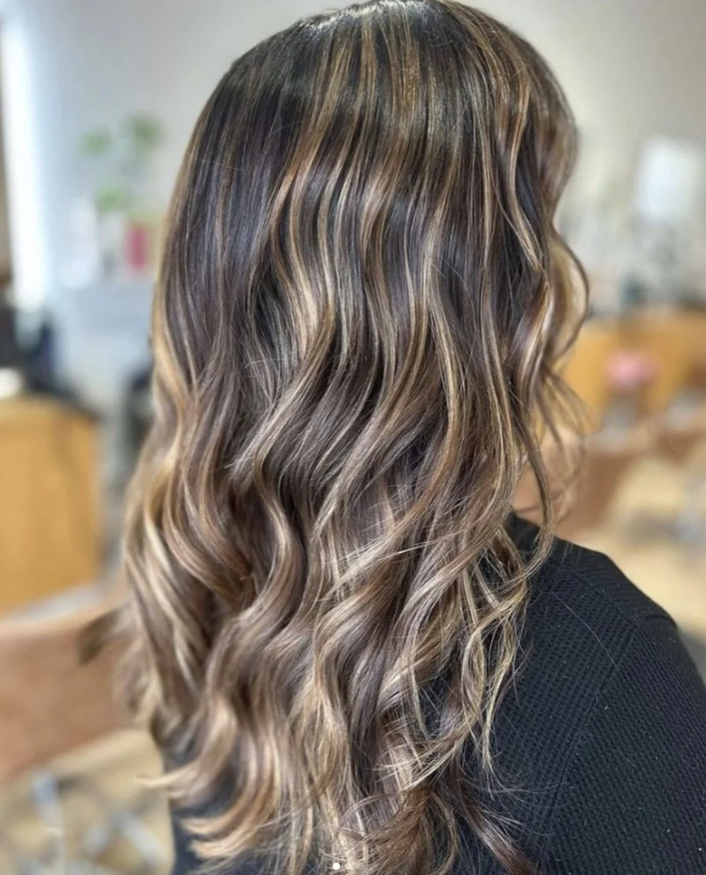 Back view of long wavy hair with caramel and beige-toned balayage from a salon portfolio