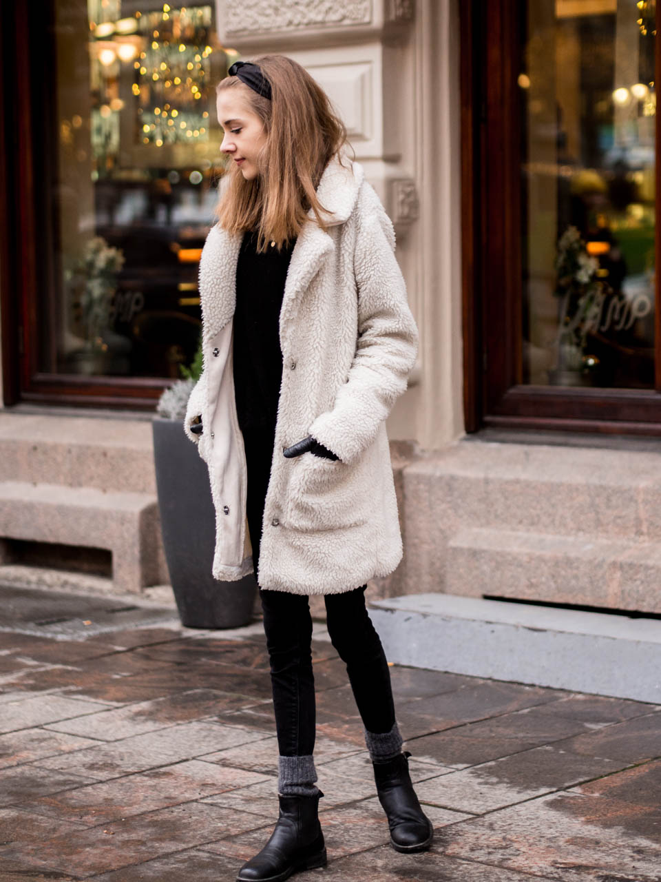 Woman wearing a cream teddy coat with black skinny jeans and black ankle boots