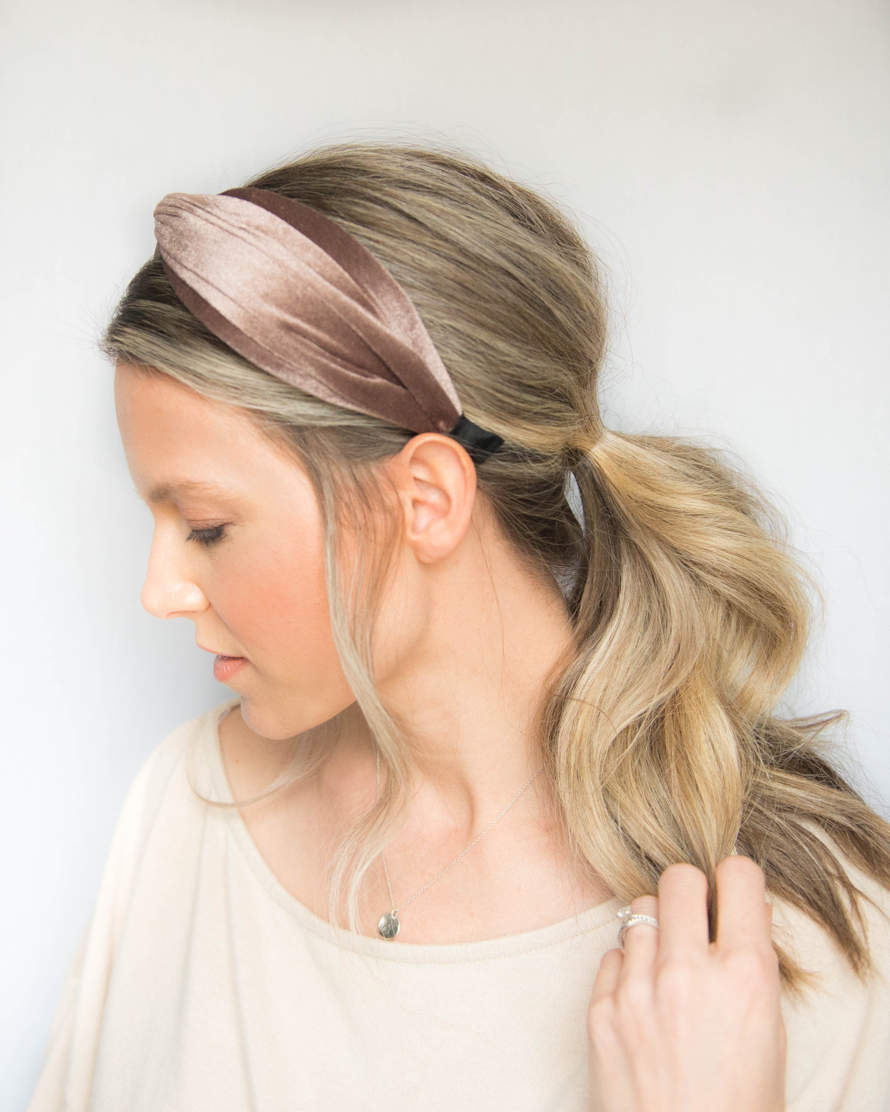 Woman with a high wavy ponytail wearing a mauve velvet twisted headband
