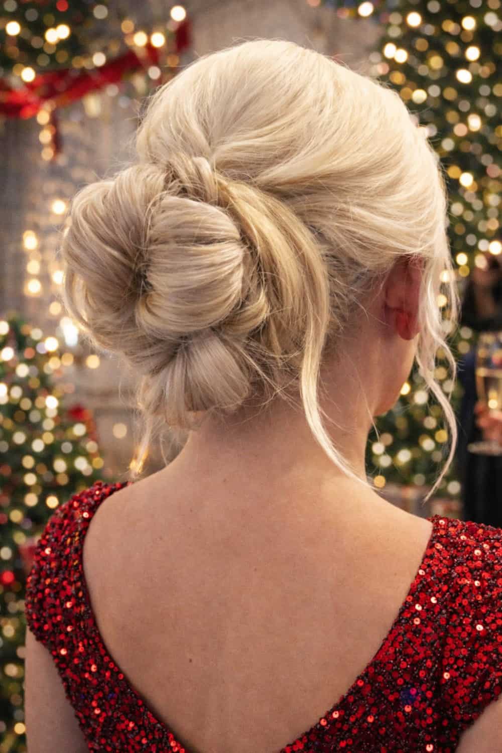 Soft low bun sitting slightly off-center with volume at the crown and loose tendrils