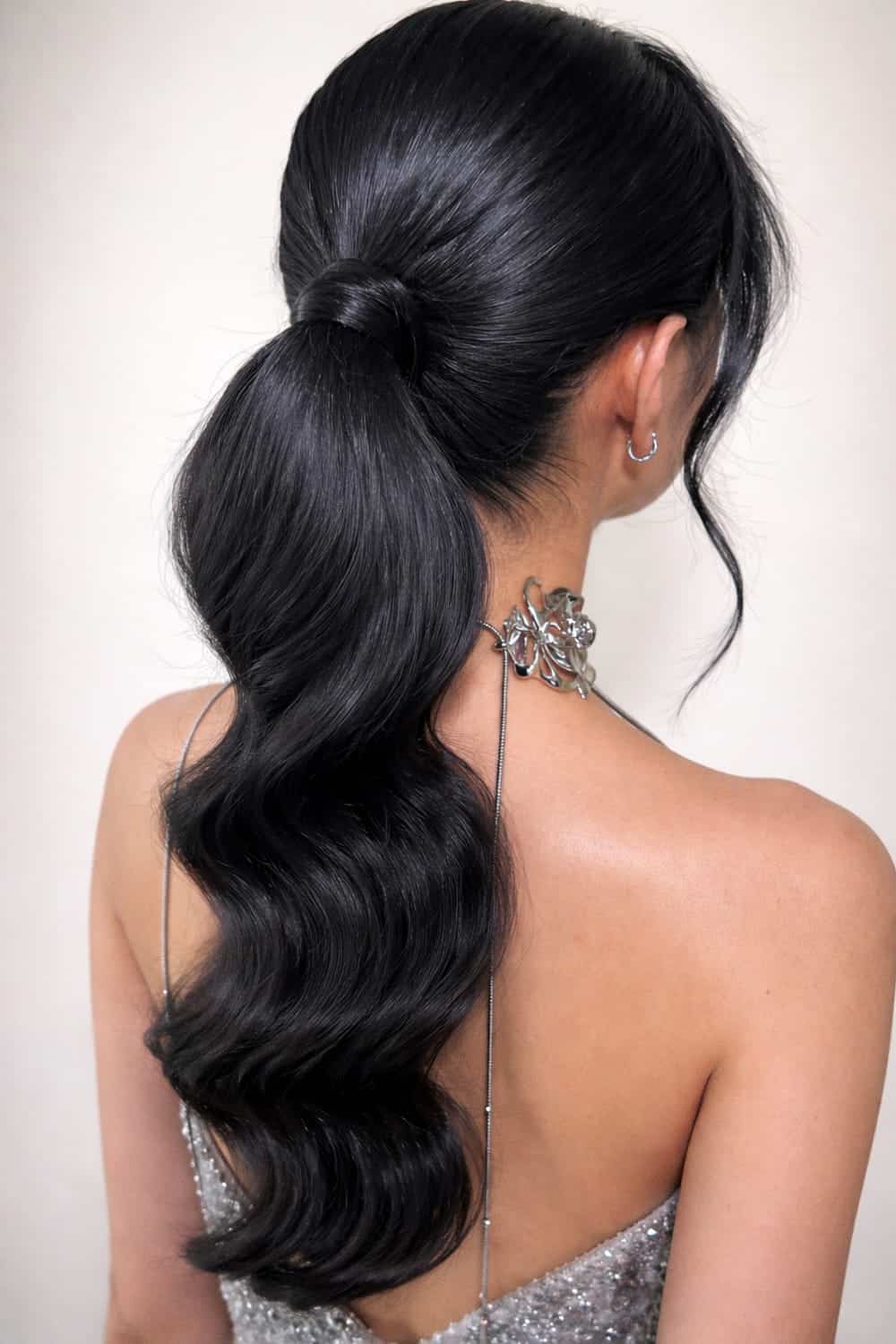Smooth low ponytail with soft waves through the length and the elastic wrapped in hair