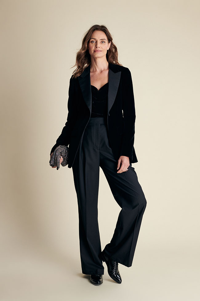 A woman wearing a black velvet tuxedo blazer with wide-leg trousers for evening