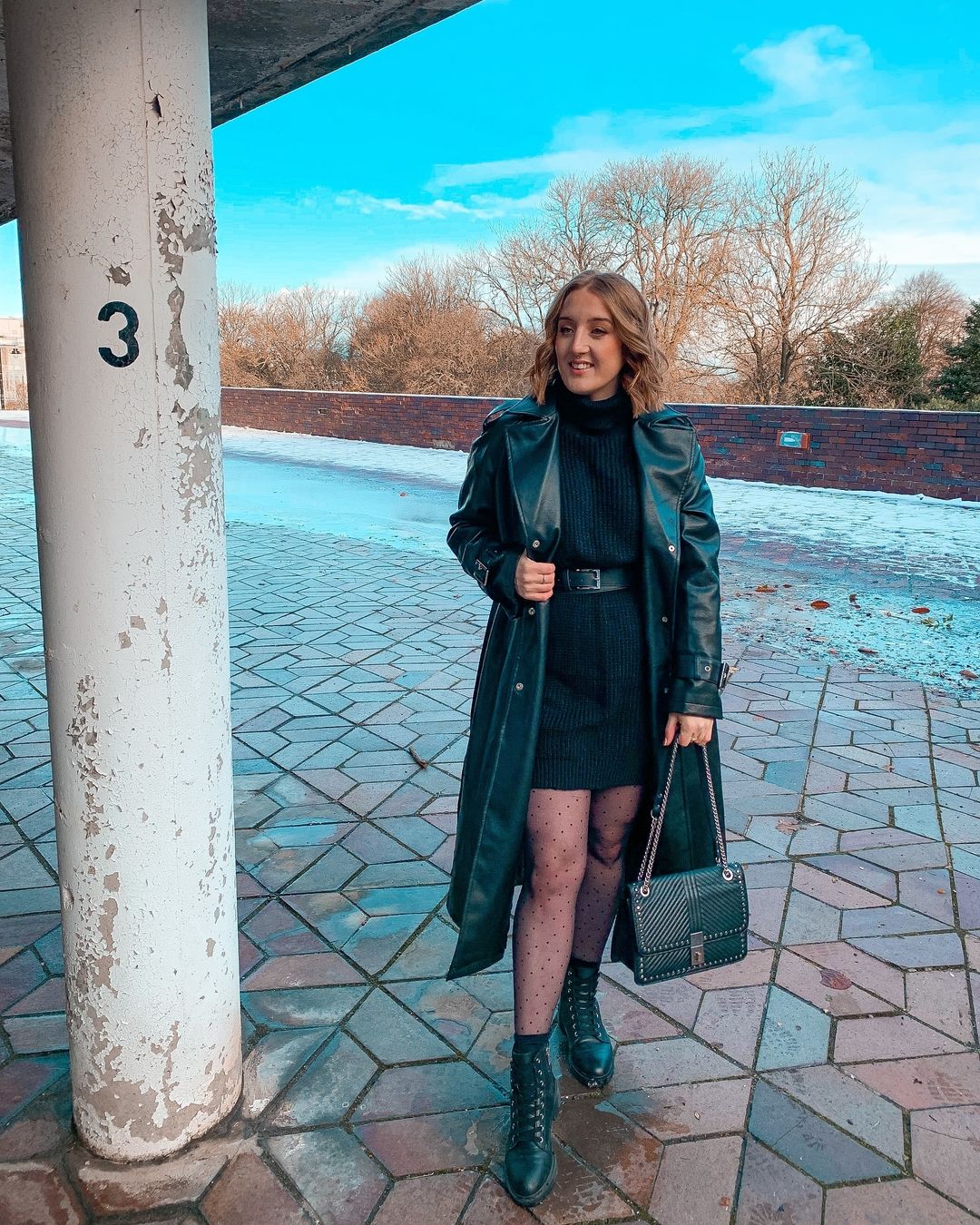 Woman in a trench coat over a sweater dress with tights and ankle boots