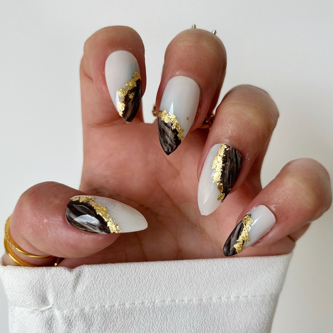 Medium almond nails in white marble with brown veins and gold foil accents