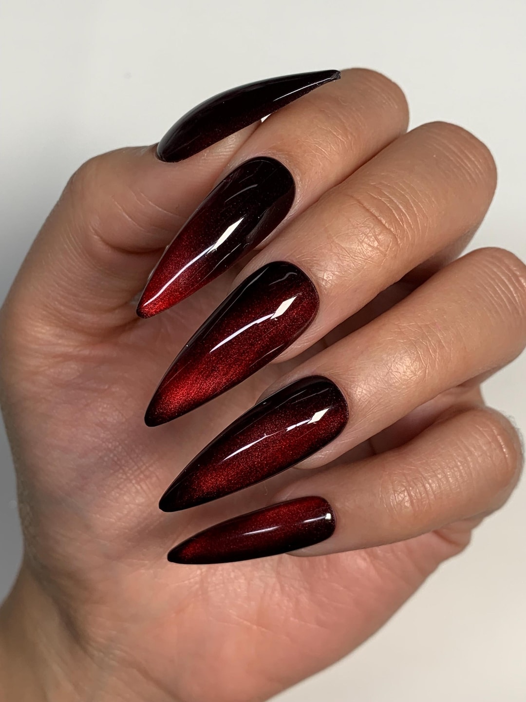 Stiletto press-on nails with a magnetic cherry red cat-eye shimmer