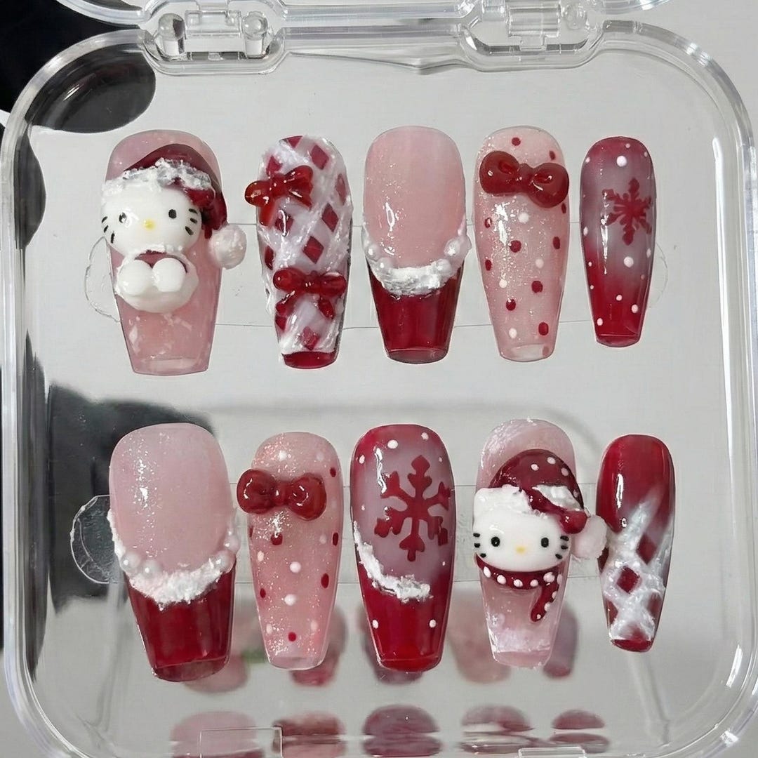 Coffin press-on nails in pink glitter and red with 3D Hello Kitty in a Santa hat, red lattice bows, fur-trim French tips and snowflakes