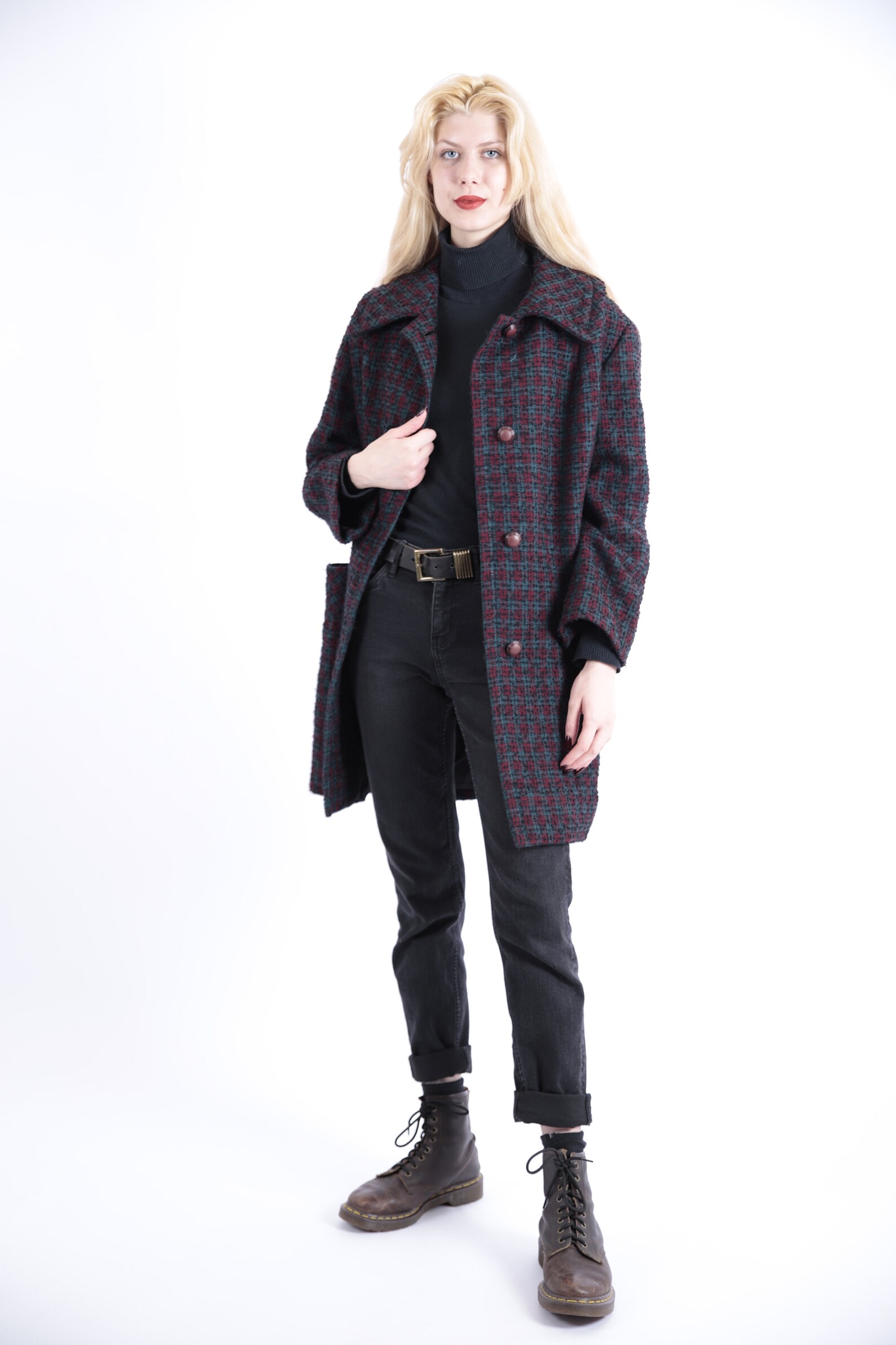 Woman in a vintage red and green plaid wool coat with black turtleneck, black jeans and lace-up boots