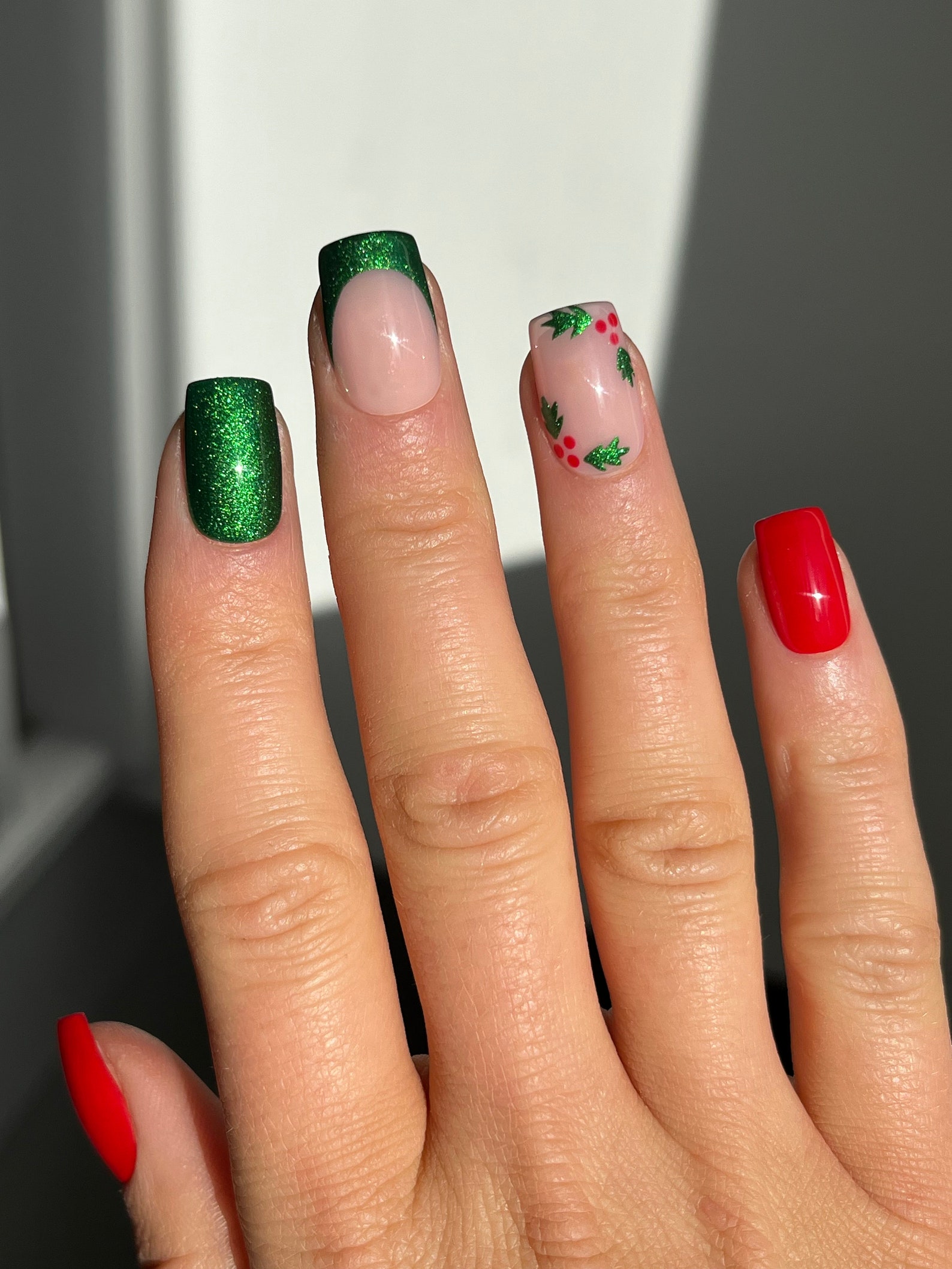 Short square Christmas nails in red and green glitter with holly leaf and berry art