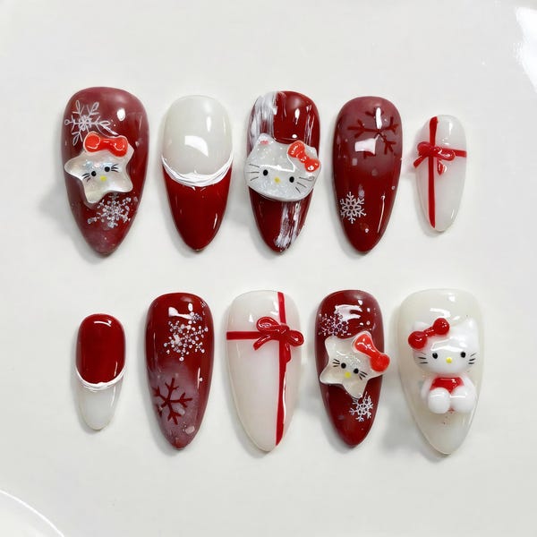Medium almond press-on nails in red and white with 3D Hello Kitty faces, gift bow nail art and snowflake decals