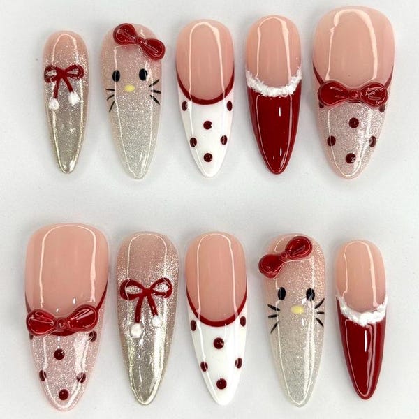 Almond press-on nails in silver glitter, white with red polka dots, red French tips with white fur trim, red bows and a Hello Kitty face
