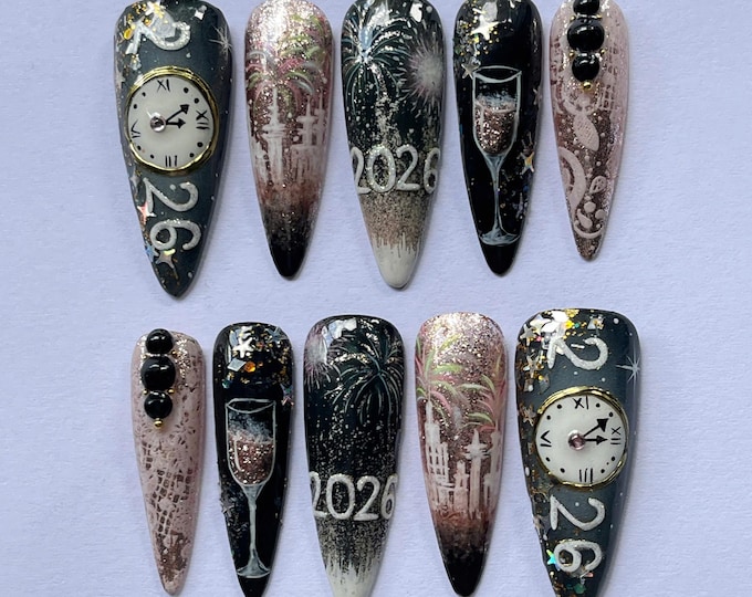 A press-on nail set with midnight clocks, fireworks, champagne glasses, and year numerals in black and pink glitter