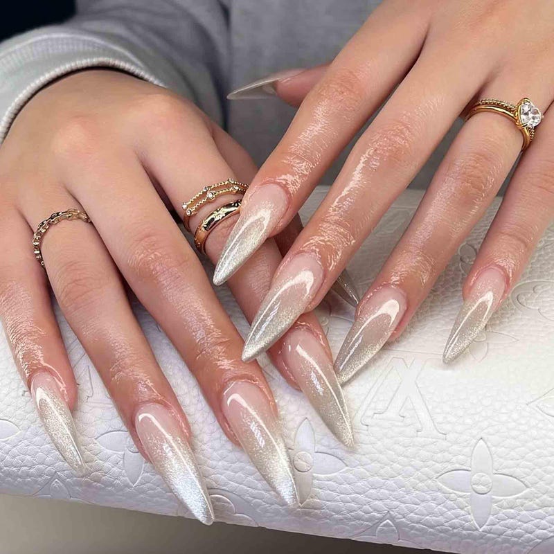 Champagne gold shimmer stiletto nails with a soft cat-eye sheen