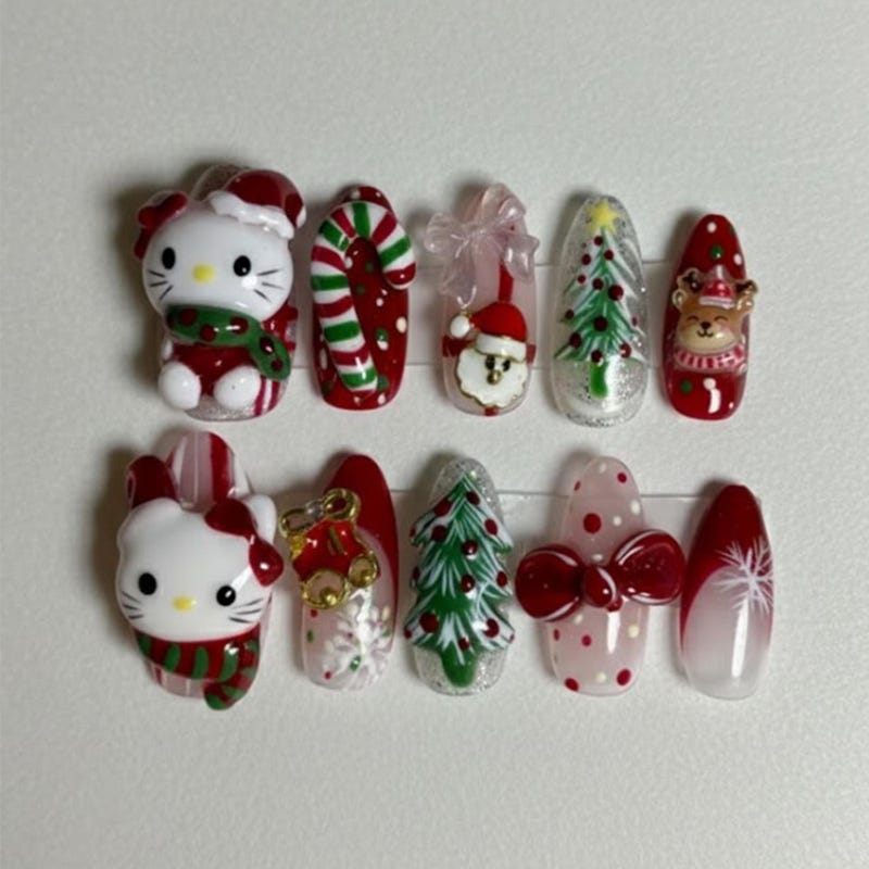 Medium almond press-on nails with 3D Hello Kitty in a Santa hat and scarf, candy canes, Christmas trees, a Santa face, a reindeer and red bows