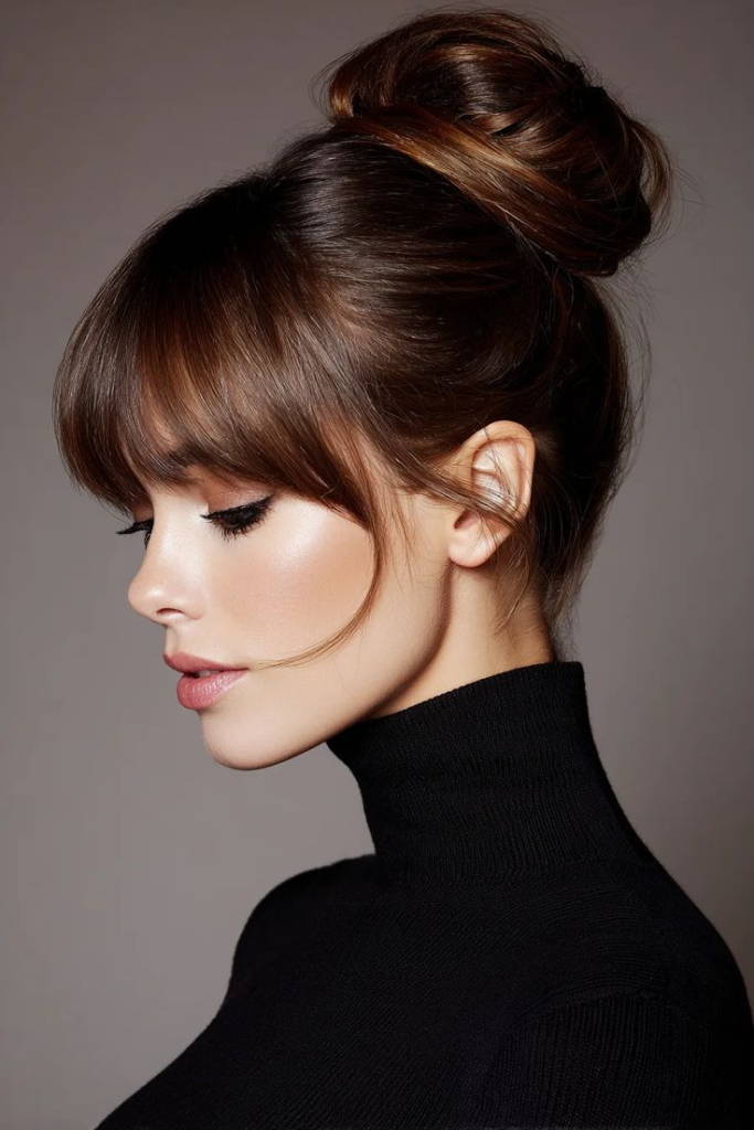 Side profile of a high bun paired with full bangs