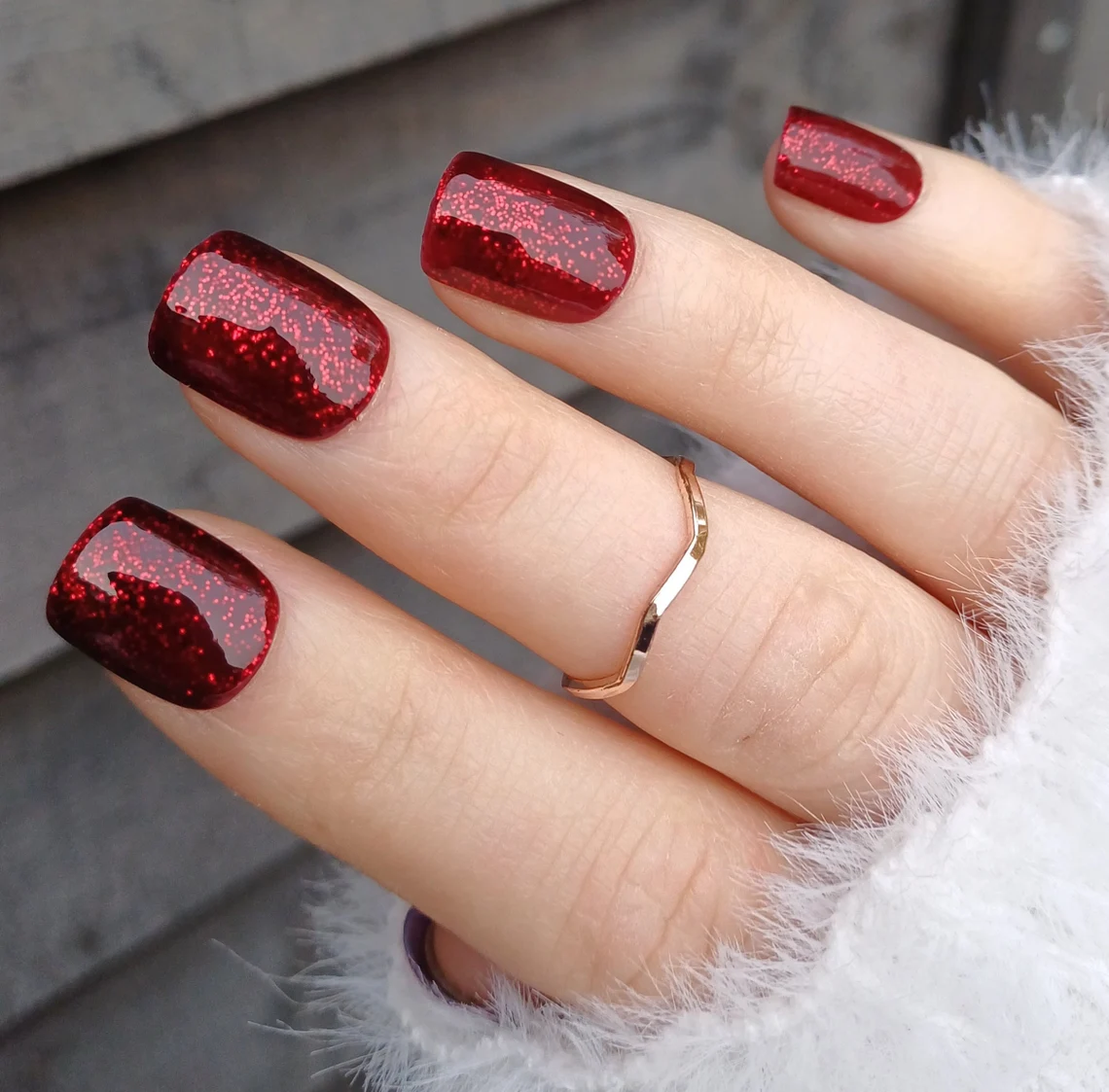 Short squoval nails in deep wine red with a fine glitter shimmer and high-gloss finish