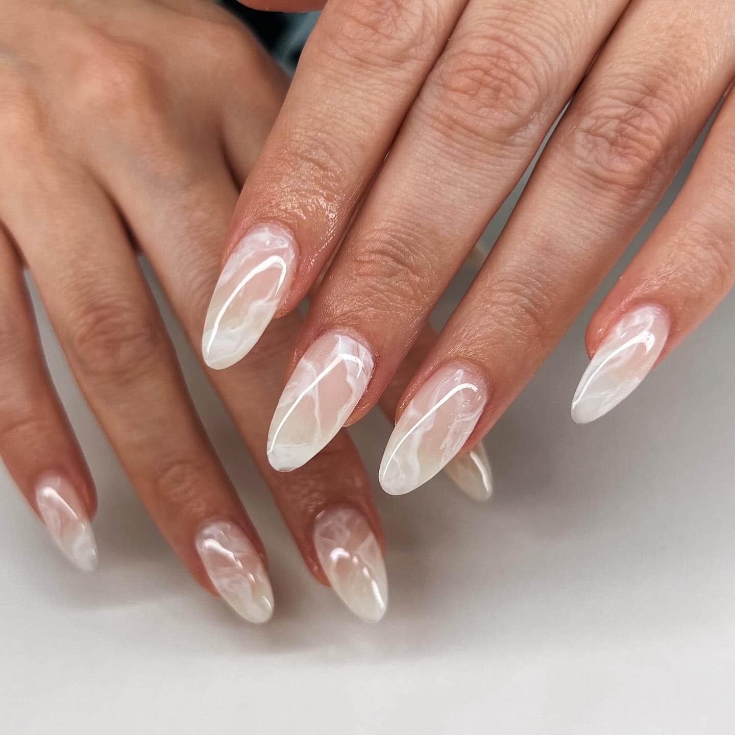 Almond nails with white marble swirls over a milky base
